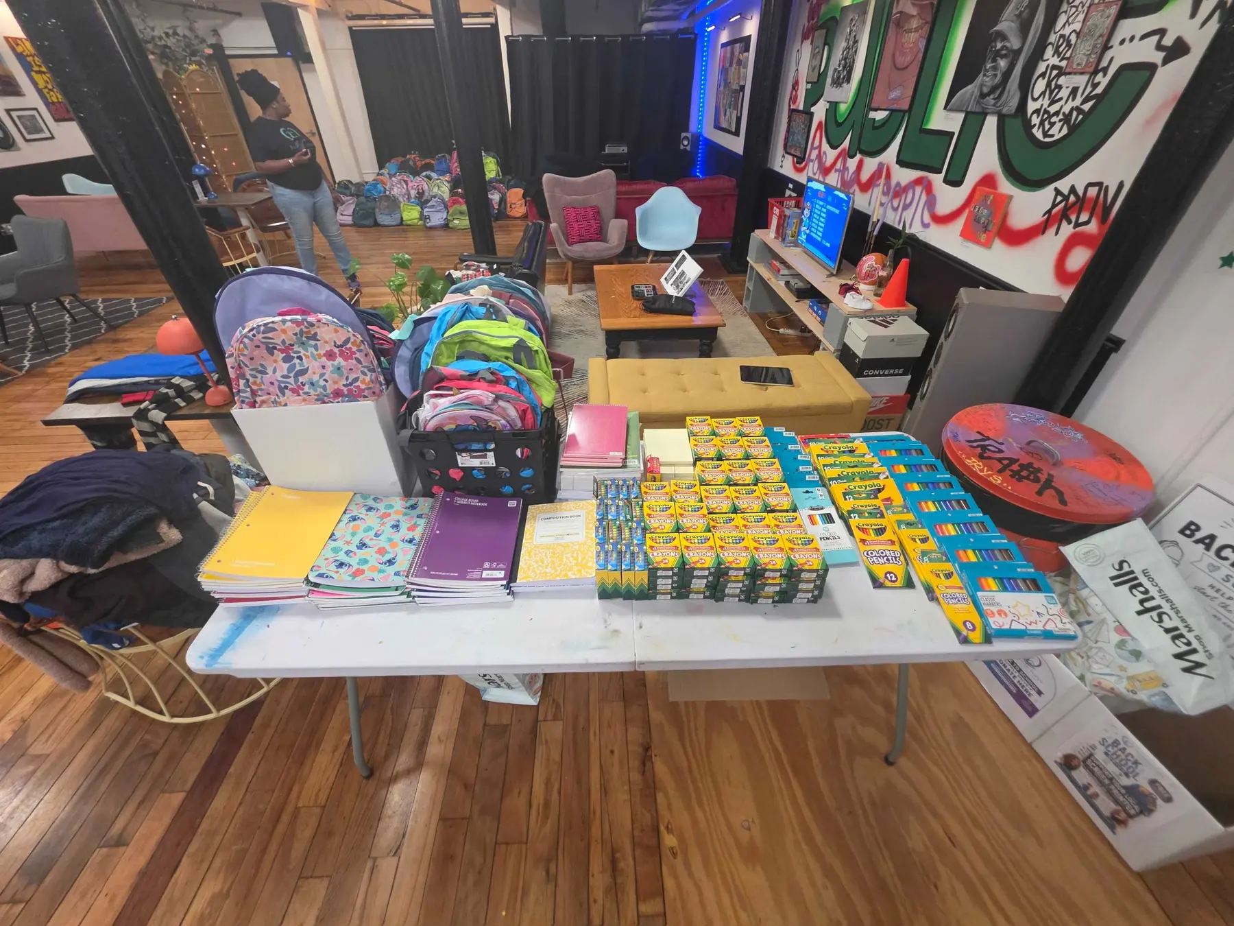 Tables filled with donated notebooks, crayons, pencils, and backpacks